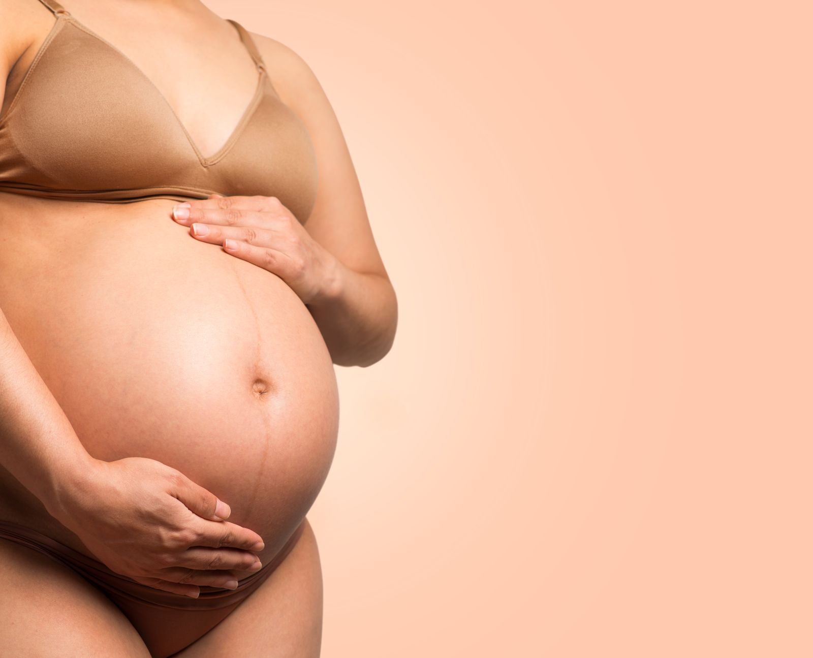 Pregnant person gently holding their belly